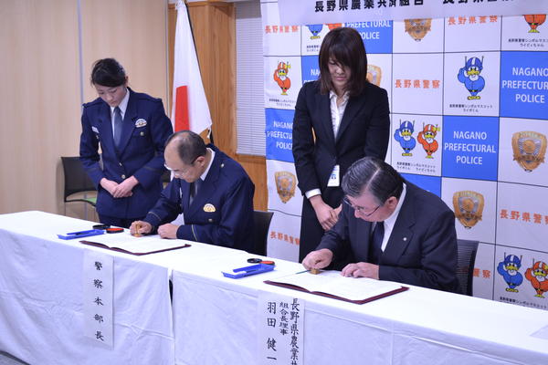 協定書に押印する内藤県警本部長（左）と羽田組合長（右）